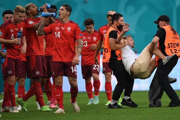 TOPSHOT - A fan who invaded the pitch is evacuated by stewards during the UEFA EURO 2020 quarter-final football match between Switzerland and Spain at the Saint Petersburg Stadium in Saint Petersburg on July 2, 2021. (Photo by Kirill KUDRYAVTSEV / POOL / AFP) (Photo by KIRILL KUDRYAVTSEV/POOL/AFP via Getty Images)